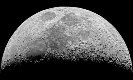 Detailed black and white photo of the moon's craters at night.