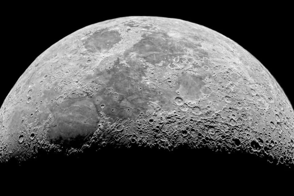 Detailed black and white photo of the moon's craters at night.
