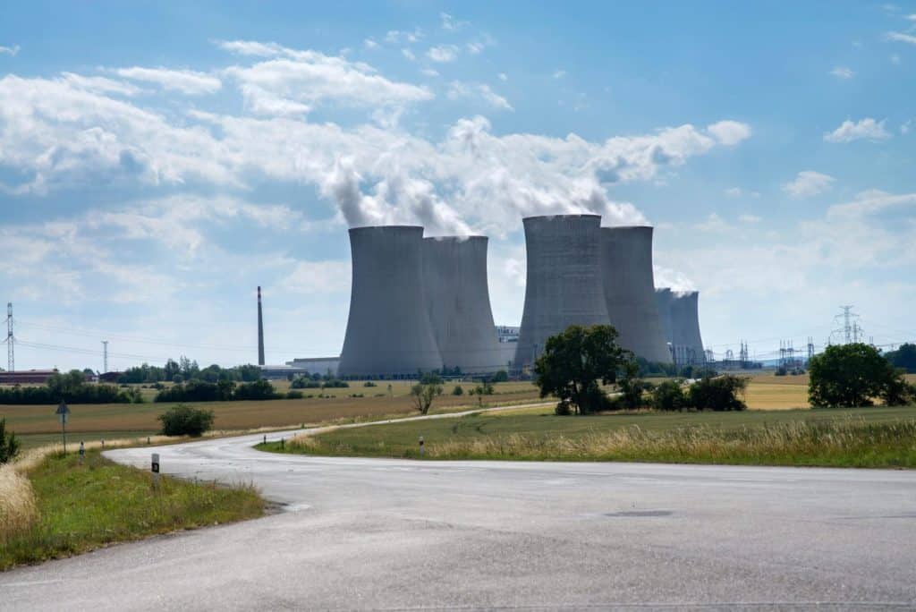 Cooling towers of Dukovany Nuclear Power Plant on a sunny day with smoke rising.