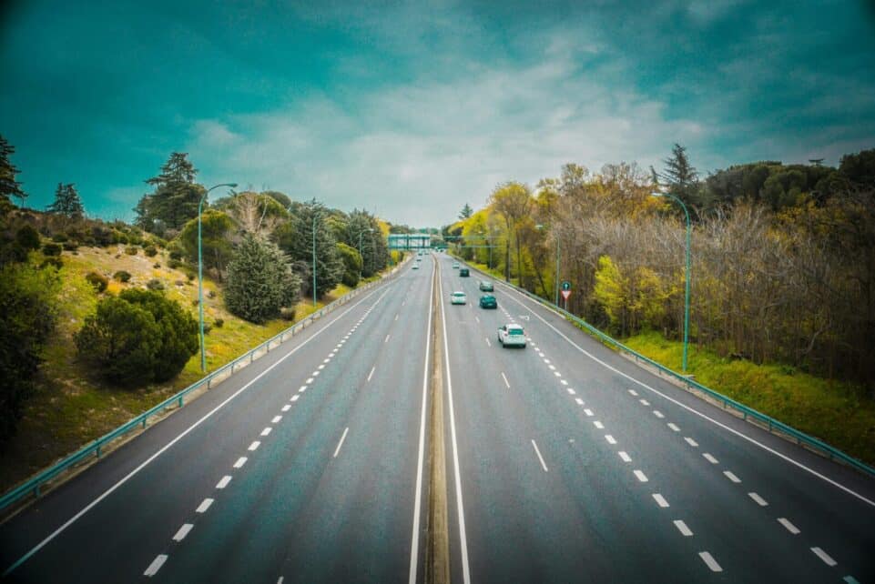 Aerial view of an open highway surrounded by trees and clear skies, perfect for travel.