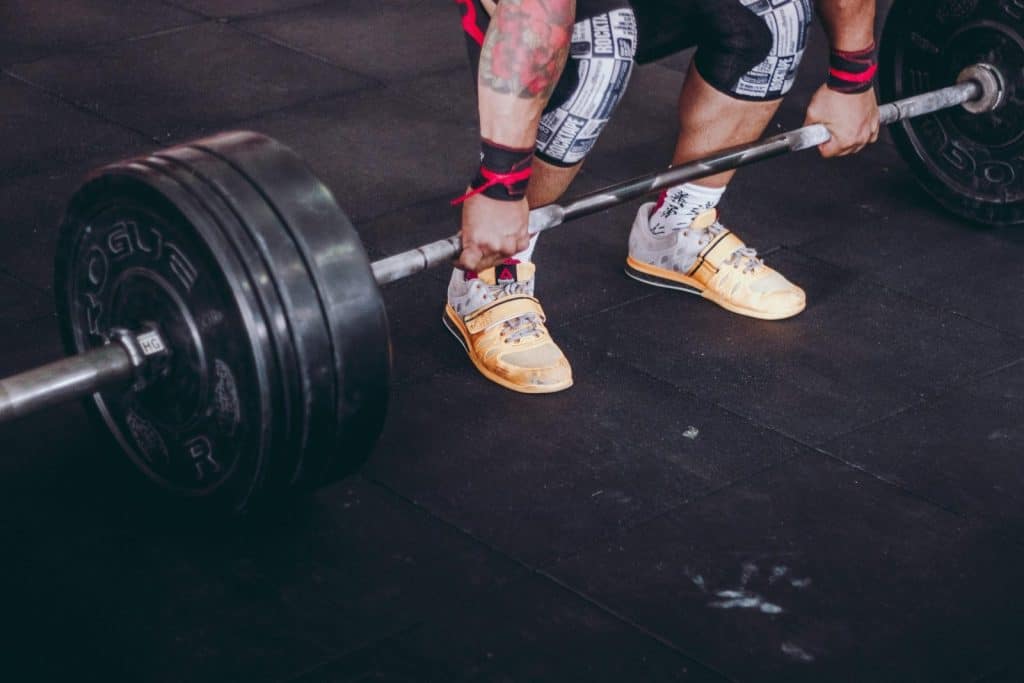 Close-up of a man performing a deadlift with a heavy barbell inside a gym. Focus on determination and strength.