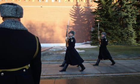Ceremonial guards in winter uniforms march by Kremlin wall, Moscow.