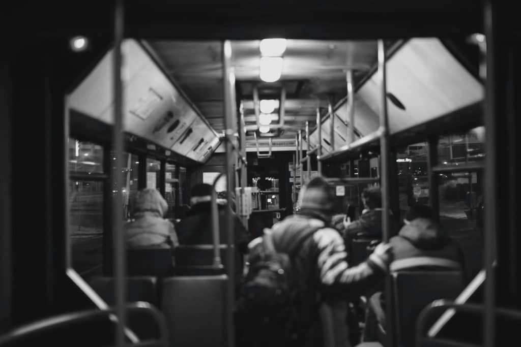 Black-and-white photo of passengers inside a city bus at night.
