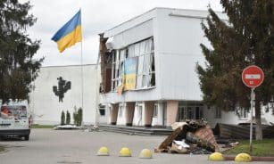 A damaged building with a Ukraine flag depicts the impact of war in an urban area.