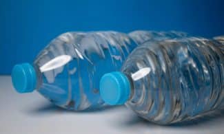 Close-up of clear plastic water bottles with blue caps on a blue background.