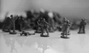 Black and white image of toy soldiers arranged in a dramatic battle pose on a reflective surface.