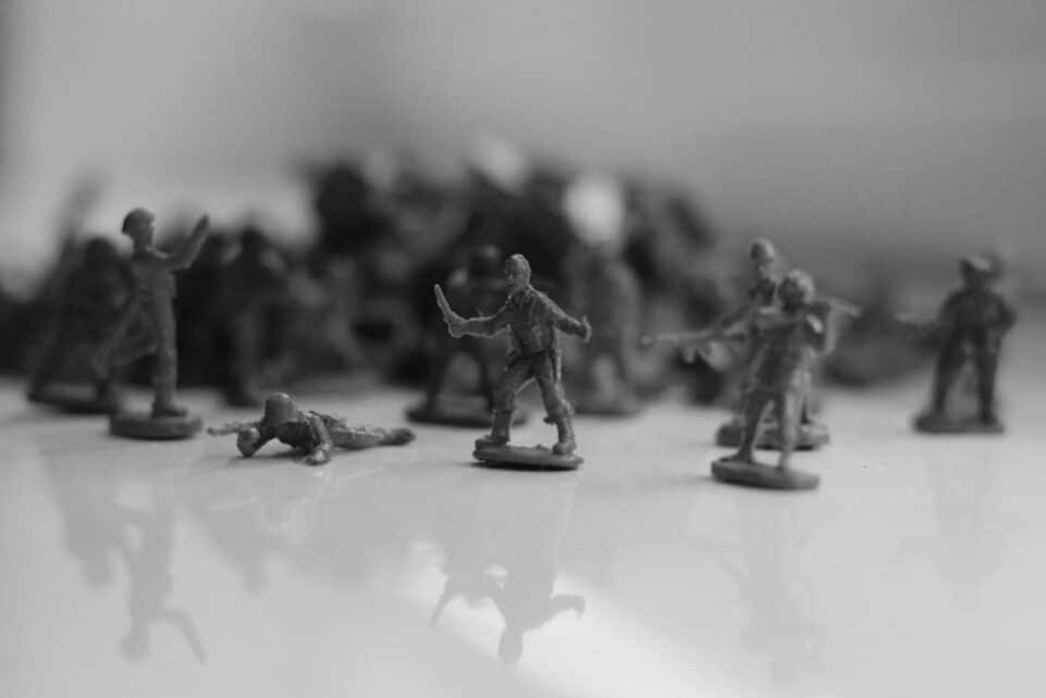 Black and white image of toy soldiers arranged in a dramatic battle pose on a reflective surface.