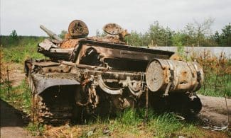 Rusted and damaged tank abandoned in Bucha, Ukraine, symbolizing conflict impact.