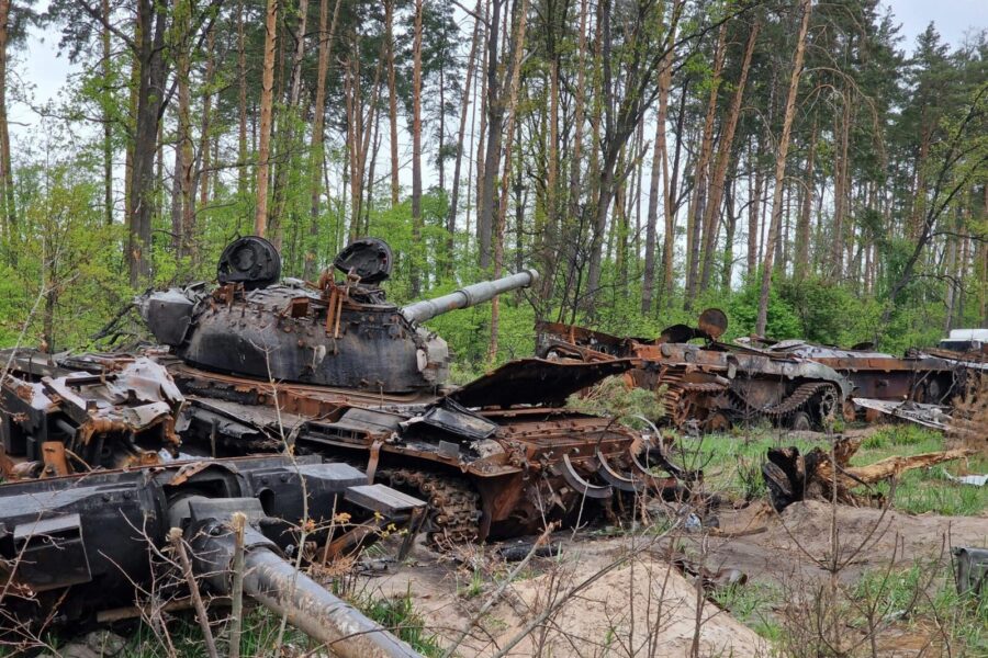 Destroyed military tanks rusting in a forest, symbolizing the aftermath of conflict and abandonment.