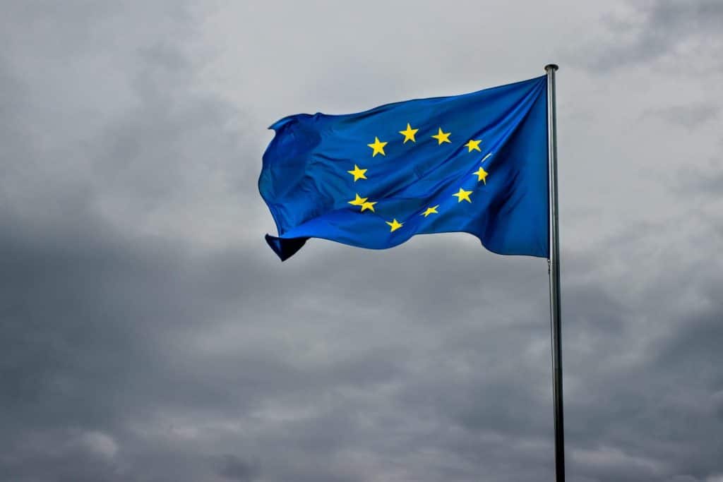 A vibrant EU flag flutters in the breeze against a dramatic cloudy backdrop. Symbol of unity.