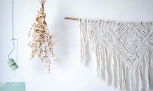 A stylish macrame wall decoration with dried eucalyptus and modern lighting.