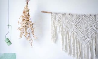 A stylish macrame wall decoration with dried eucalyptus and modern lighting.