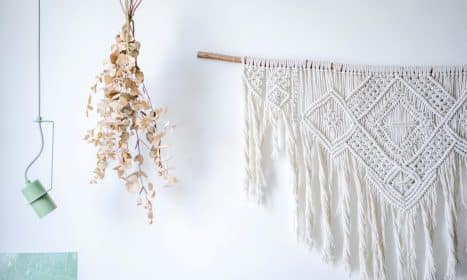 A stylish macrame wall decoration with dried eucalyptus and modern lighting.
