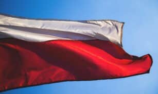 Close-up of a Polish flag waving against a clear blue sky, symbolizing patriotism and national pride.