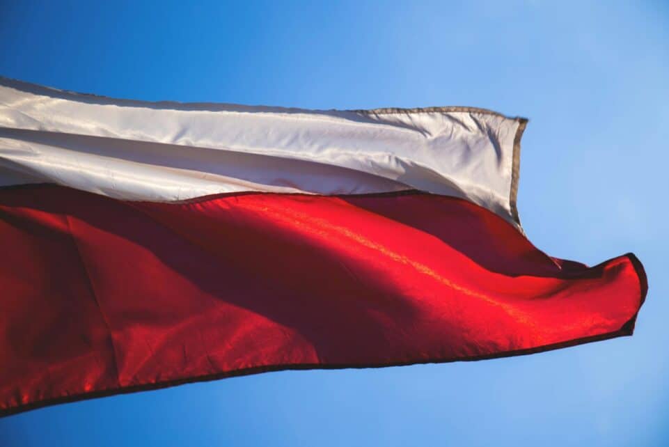 Close-up of a Polish flag waving against a clear blue sky, symbolizing patriotism and national pride.