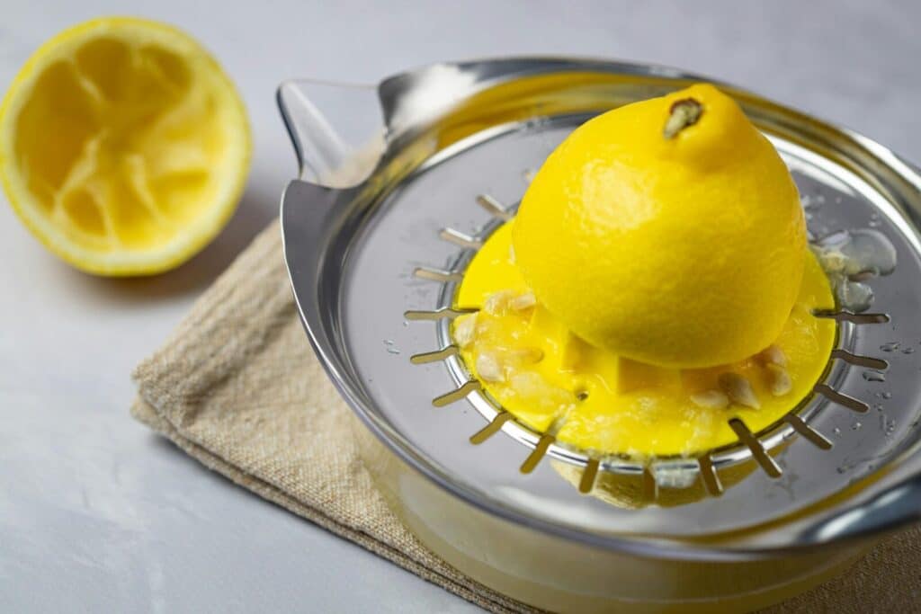 Close-up of a lemon being juiced on a metal citrus juicer, emphasizing freshness and health.