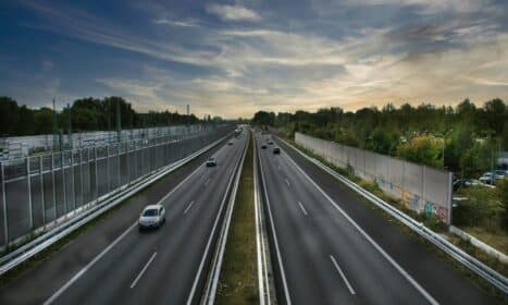 Aerial shot of a highway with minimal traffic against a dramatic sky backdrop.