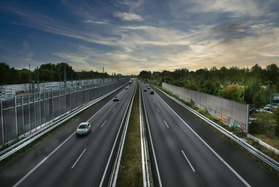 Aerial shot of a highway with minimal traffic against a dramatic sky backdrop.