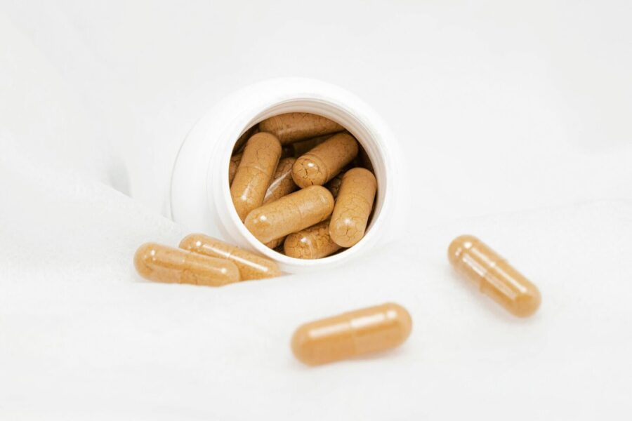 Brown capsules spilling from a white bottle on a bright white background, ideal for health and wellness themes.