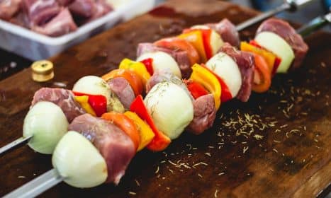 Close-up of freshly prepared barbecue skewers with meat and veggies on a wooden board.