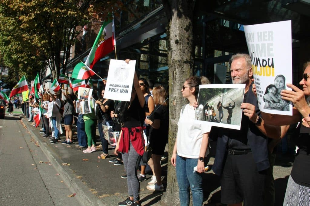 A peaceful protest in Vancouver advocating for Iranian rights with flags and placards.