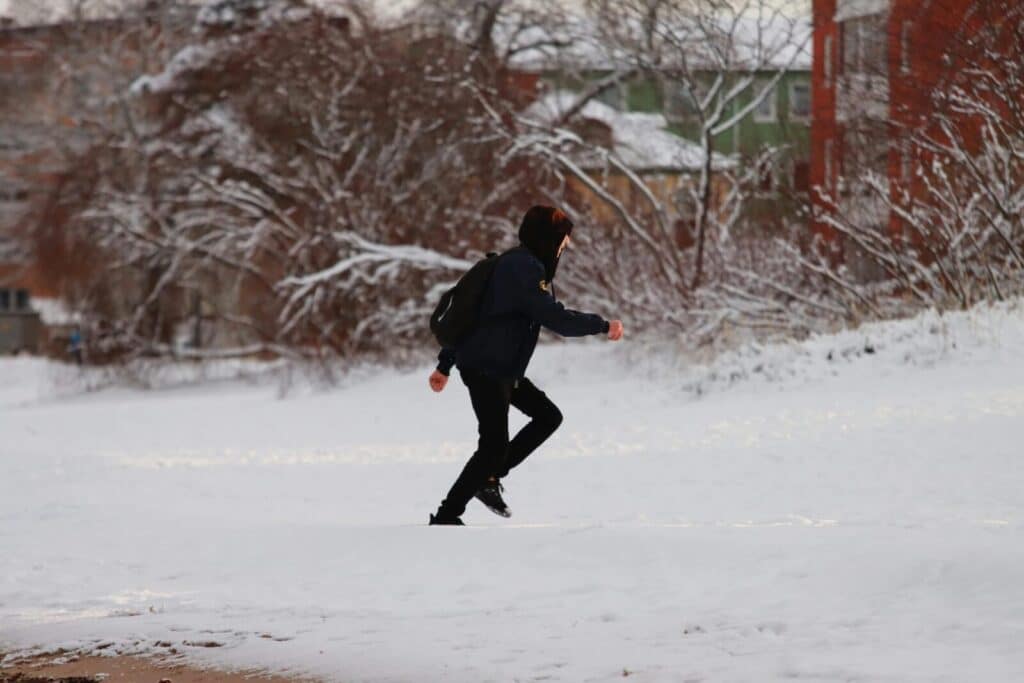 Person running in a snowy winter landscape with residential background.