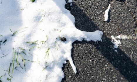 Close-up of melting snow on asphalt with grass in Sankt Anton am Arlberg.