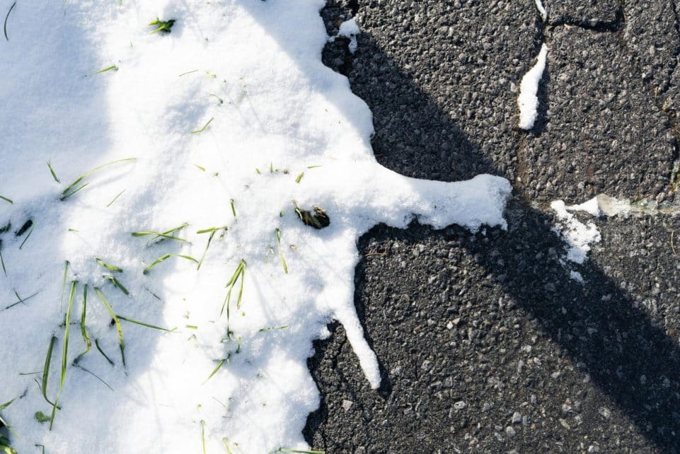 Close-up of melting snow on asphalt with grass in Sankt Anton am Arlberg.