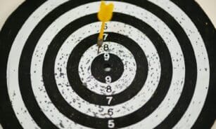 Close-up of a dart hitting the bullseye on a black and white target board symbolizing success.