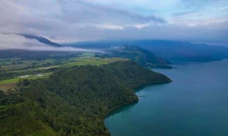 Scenic aerial view of Lake Toba's lush green coastline in North Sumatra, Indonesia.