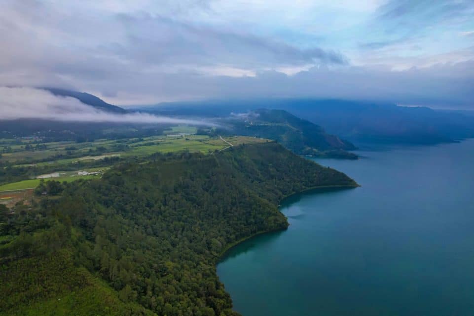Scenic aerial view of Lake Toba's lush green coastline in North Sumatra, Indonesia.