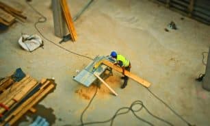 Overhead view of a construction worker using a saw to cut wood at a construction site.