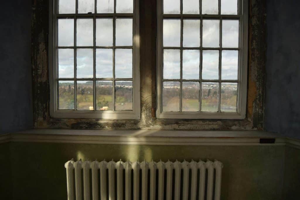 Interior view with an old window, radiator, and scenic countryside outside.