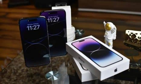 Close-up of Apple iPhone 14 Pro Max with astronaut figurine on a reflective surface.