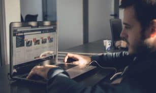Adult man using laptop to browse an online marketplace in a modern office.