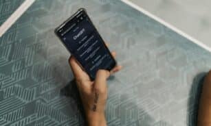 Close-up of a person holding a smartphone displaying the ChatGPT application interface on a patterned table.