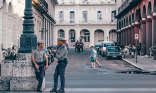 Police officers conversing in a scenic Havana street, showcasing historic architecture.