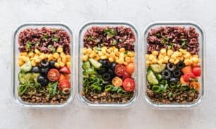 Colorful healthy meal prep with corn, olives, tomatoes, and lentils in glass containers. Perfect for mindful eating.