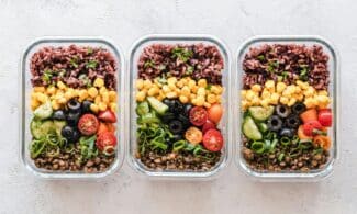 Colorful healthy meal prep with corn, olives, tomatoes, and lentils in glass containers. Perfect for mindful eating.