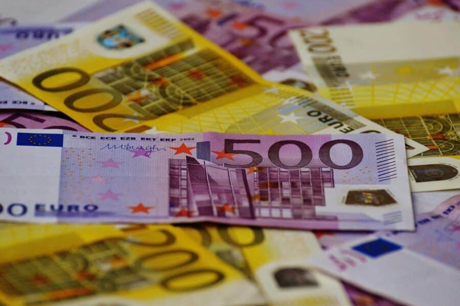 A close-up image of several Euro banknotes arranged in a scattered manner.