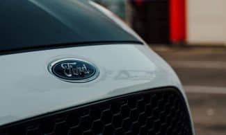 Detailed close-up image showcasing a white Ford car emblem on the vehicle's grille.