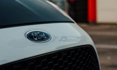 Detailed close-up image showcasing a white Ford car emblem on the vehicle's grille.