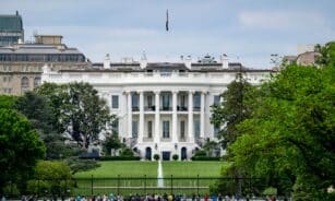 A scenic view of The White House, a renowned landmark in Washington, DC, surrounded by greenery and tourists.