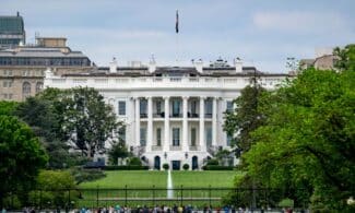 A scenic view of The White House, a renowned landmark in Washington, DC, surrounded by greenery and tourists.