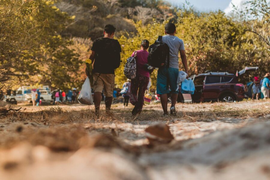 A group of young adults walking towards a gathering in nature, enjoying a sunny day.