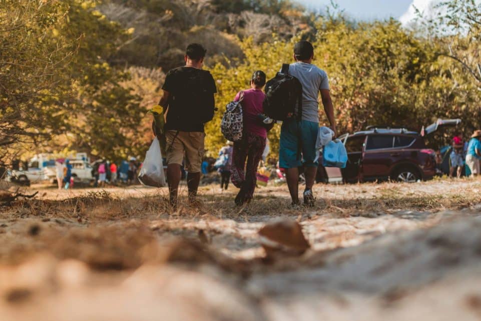 A group of young adults walking towards a gathering in nature, enjoying a sunny day.