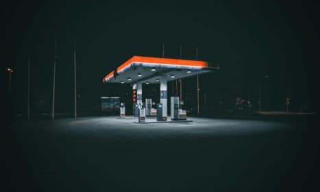 An isolated and illuminated gas station at night, highlighting urban solitude under a dark sky.