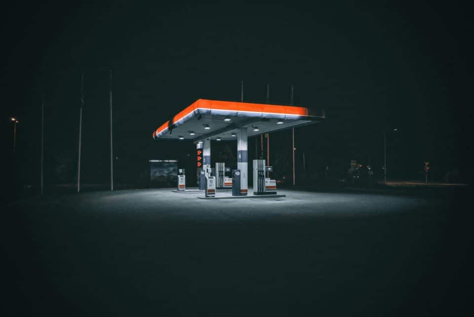 An isolated and illuminated gas station at night, highlighting urban solitude under a dark sky.
