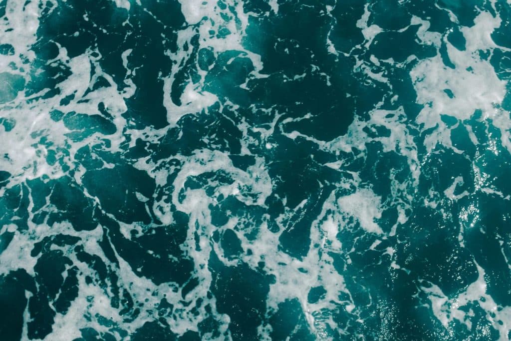 Dynamic aerial photograph of ocean waves with foamy textures, showcasing sea patterns.