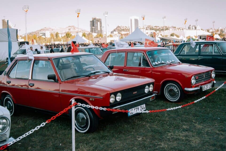 Classic Fiat cars showcased during a lively Turkish car exhibition outdoors.